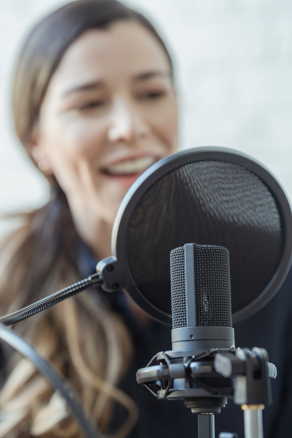 Happy woman smiling while recording voice with microphone